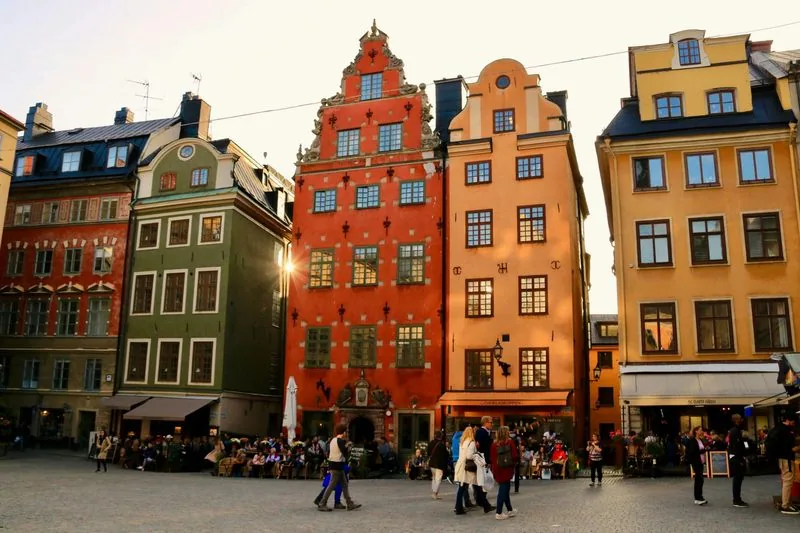 Bunte Giebelhäuser in Rot, Ocker und Grün am Stortorget in Stockholms Altstadt Gamla Stan, Café-Terrassen davor