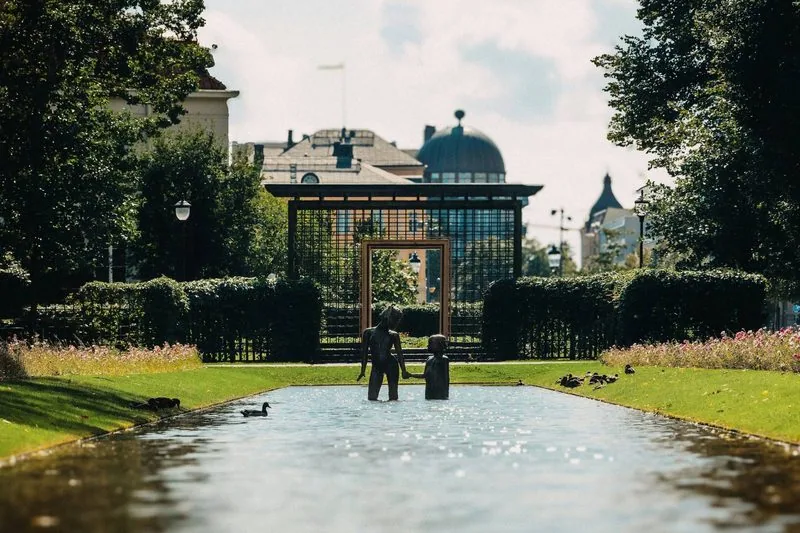 Park mit langem Wasserbecken, Hecken und Blumen, im Hintergrund ein Kuppelbau