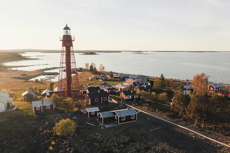 Roter Leuchtturm und Häuser an der Küste bei Skellefteå im Abendlicht